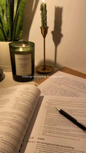 舒適的書桌，有打開的書本、筆、蠟燭和多肉植物，在溫暖的燈光下。 — 讀書 壁紙