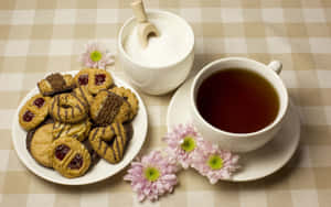 一杯茶配上各式餅乾和粉紅色花朵，置於格子桌布上。 — MacBook Air M1 壁紙