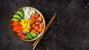 色彩繽紛的 poke bowl，有三文魚、芒果、酪梨和米飯，放在深色石上，附筷子。 — 壽司 壁紙