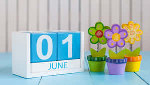 6月1日日曆塊與藍色木桌上的彩色玩具花盆。 — 七月 壁紙
