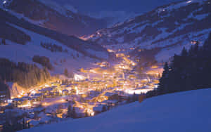 被雪覆蓋的山村在夜晚被溫暖的燈光照亮。 — 冬季風景 壁紙