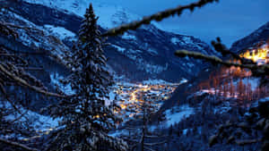 被雪覆蓋的山村在黃昏時分被溫暖的燈光照亮。 — 冬季風景 壁紙