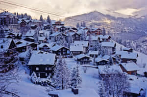 暮色天空下，雪白的阿爾卑斯山村，有木屋和松樹 — MacBook Air 壁紙
