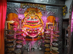 一個色彩繽紛的印度教神龕，帶有花環和供品。 — Maa Durga 壁紙