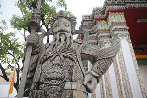 裝飾華麗的寺廟中的守護神石像，有綠樹和色彩繽紛的建築。 — 雕塑 壁紙