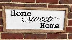 木牌上寫有「Home sweet Home」文字，安裝在磚牆上。 — 甜蜜的家 壁紙