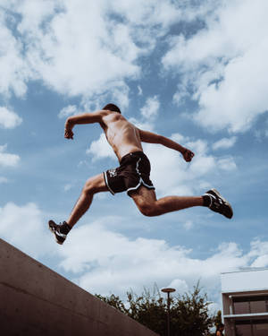 運動型男人在半空中跳躍，背景是藍天白雲 — 跑酷 壁紙
