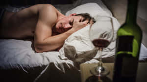 一個男人在酒杯和酒瓶旁邊的床上睡覺。 — 醉意朦朧 壁紙