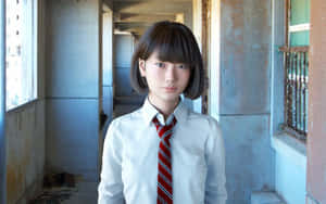 一個身穿校服的小女孩站在破舊的走廊裡。 — 日式 壁紙