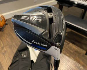 TaylorMade SIM高爾夫球桿，9.0桿面傾角，置於室內木地板 — 5:4 壁紙