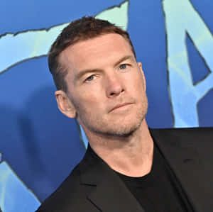 穿著黑色西裝外套的男人，表情嚴肅，背景為藍色圖形。 — 印象派 壁紙