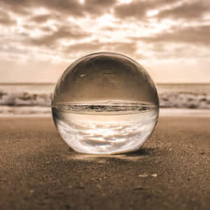 沙灘上的玻璃球反射日落海浪和天空 — 海灘 壁紙