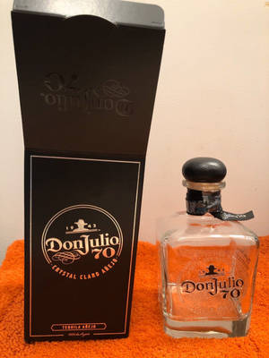 Don Julio 70龍舌蘭酒瓶和盒子在橙色毛巾上 — 黑色 壁紙