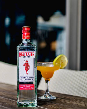 Beefeater琴酒瓶和雞尾酒在晚上的木桌上 — Apple Watch 壁紙