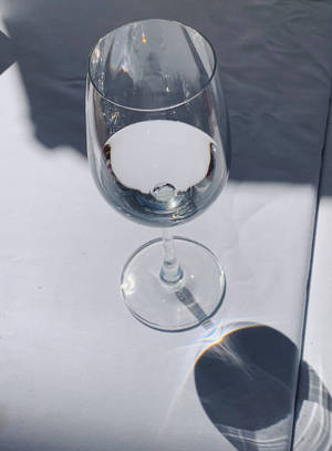 白色表面上的透明酒杯，強烈的陽光和陰影。 — Bugatti iPhone 壁紙
