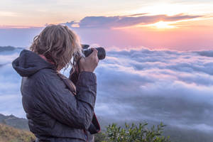 從山上拍攝雲海之上日出的人 — 攝影 壁紙