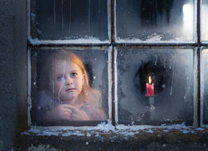一個小女孩在夜晚，旁邊點著一支紅蠟燭，望著積雪的窗外。 — 可愛女孩 壁紙