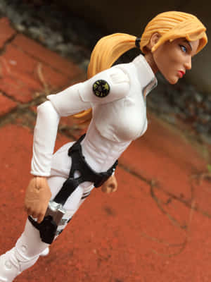 金髮動作公仔穿著白色S.H.I.E.L.D.制服蹲在紅色磚上。 — 2048x2732 壁紙