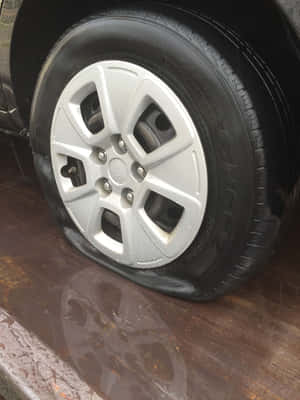 潮濕木質表面上的扁平汽車輪胎與銀色輪圈。 — 弗萊克斯·惠勒 壁紙