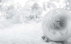銀色雪花設計的聖誕裝飾品躺在雪地上，閃爍著光芒。 — 聖誕美學 壁紙