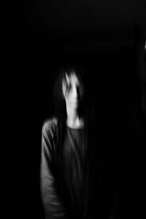一個在黑暗黑白場景中長髮的模糊鬼影。 — 粉紅色美學桌面 壁紙