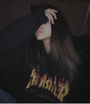 穿黑色連帽衫的人在室內昏暗燈光下遮住臉。 — Thrasher 壁紙