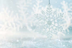 一個懸掛的閃亮雪花裝飾品，在冬季場景中閃爍。 — MacBook Air M3 壁紙