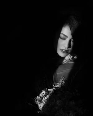 一個閉著眼睛的女人在黑暗、戲劇性的肖像中拿著一束花。 — 昏暗 壁紙