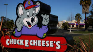 Chuck E Cheese 吉祥物雕像在陽光普照的日子於餐廳入口揮手。 — 查克芝士 壁紙