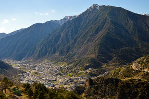 山谷中的山城，在清澈藍天下有白雪覆蓋的山峰。 — 城市 壁紙