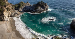 海岸小海灣，碧綠色海浪拍打沙灘，瀑布從懸崖傾瀉而下。 — 自然 壁紙