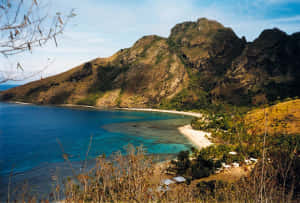 熱帶海灘，背景是碧綠的海水和綠色的山脈。 — 斐濟 壁紙
