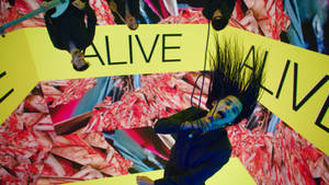 人物被懸掛尖叫，頭髮尖尖，背景為黃色「ALIVE」和紅色碎片。 — 1975樂團 壁紙