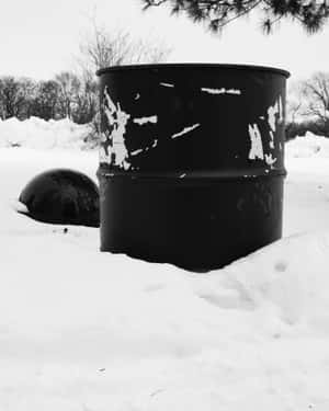 黑色桶和圓頂部分埋在雪中，背景有光禿的樹木。 — 4:5 壁紙