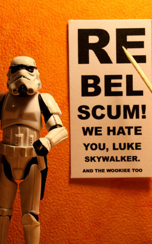 風暴兵玩具旁邊有一個寫著 rebel scum we hate you luke skywalker and the wookiee too 的標誌。 — Galaxy Tab S9 壁紙