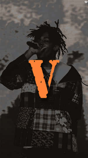 一個有辮子的說唱歌手拿著帶有橙色V圖形的麥克風。 — Vlone 壁紙