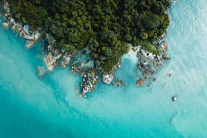 一個熱帶島嶼的鳥瞰圖，有碧綠的海水和岩石海岸。 — 免費 壁紙