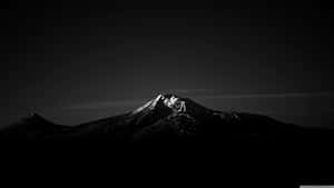 積雪的山頂在深色天空的映襯下閃耀。 — 美學 Mac 壁紙