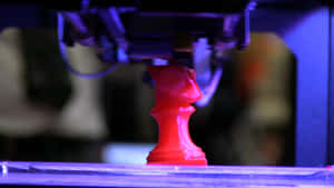 一個紅色西洋棋棋子正在藍光下由3D列印機列印。 — 3D 壁紙