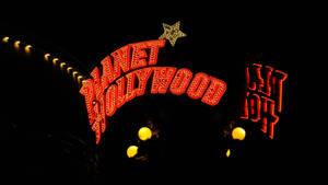 Planet Hollywood 霓虹招牌在夜晚與星星和溫暖燈光一同閃耀。 — 乾淨 壁紙