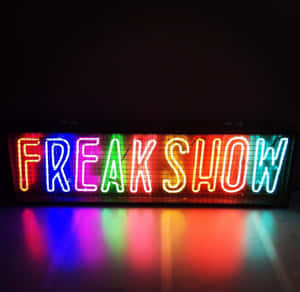 一個色彩繽紛的霓虹燈牌，上面寫著 freak show，彩虹燈光在黑暗表面上反射。 — 城市燈光 壁紙