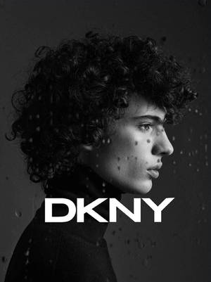 在DKNY廣告中，有捲髮的人物透過玻璃上的雨滴側視。 — 品牌 壁紙