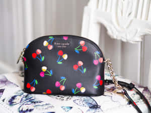黑色櫻桃圖案Kate Spade包，帶鏈條肩帶，放在蝴蝶布料上。 — Kate spade 壁紙