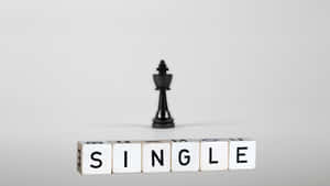 黑色西洋棋國王位於由木塊組成的「SINGLE」一詞上方。 — 獨自一人 壁紙