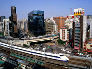 一列高速列車穿過繁華的日本城市景觀，高樓大廈和繁忙街道盡收眼底。 — 日式審美桌面 壁紙