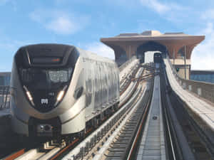 藍天下，現代銀色列車在高架軌道上駛向未來感車站。 — 地鐵 壁紙