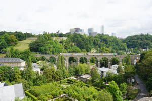火車在石拱橋上，下方是綠色花園，背景是城市天際線。 — 史丹佛橋 壁紙