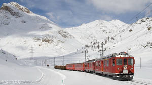紅色火車在雪地軌道上穿越阿爾卑斯山脈，藍天背景 — 火車 壁紙