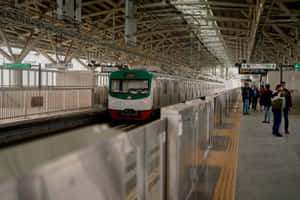 乘客在火車月台上等候，一列綠色和白色的火車正在接近。 — 地鐵 壁紙