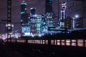 火車在夜晚快速駛過燈火通明的現代城市。 — 莫斯科 壁紙